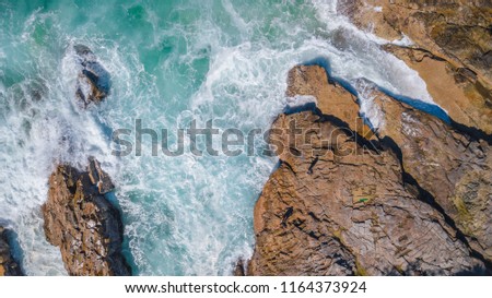 Drone shot of a rocky headland at daylight with emerald color water