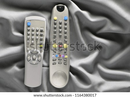 TV remote controls on a gray silk background
