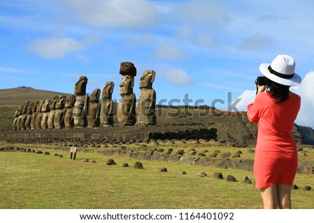Young woman taking pictures of the famous Moai statues at Ahu Tongariki on Easter Island, Archaeological site in Chile