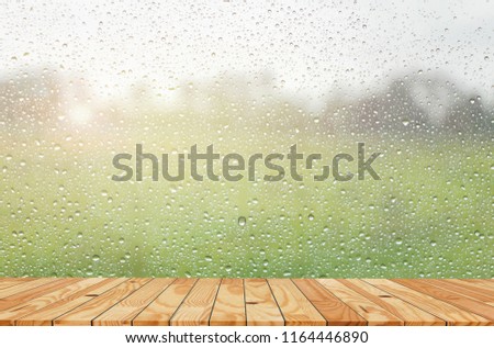 Wooden balcony with view through glass from inside the home, flare with raindrops.