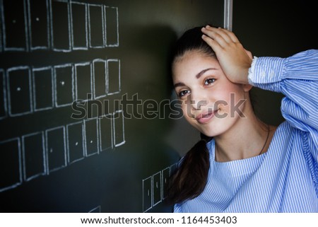 Upset student stay near blackboard in classroom