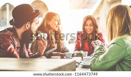 Happy trendy people having breakfast inside bar restaurant patio - Young millennials friends drinking coffees and eating muffins in morning time - Fashion and lifestyle concept - Focus on left man ear Royalty-Free Stock Photo #1164473749