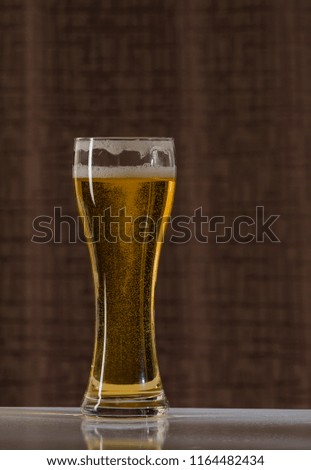 Glass of light beer on table and Brown background.