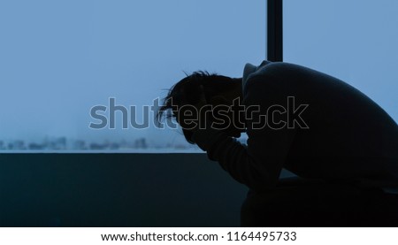 PTSD Mental health concept, Young depressed asian man sitting alone near window in evening time with low light environment, Copy space, selective focus. Royalty-Free Stock Photo #1164495733