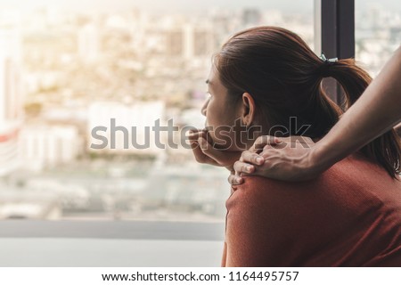PTSD Mental health concept, Psychologist sitting and touch young depressed asian woman for encouragement near window with low light environment.Selective focus. Royalty-Free Stock Photo #1164495757