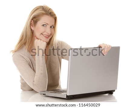 pretty blond woman wearing beige swether, sitting down and using laptop