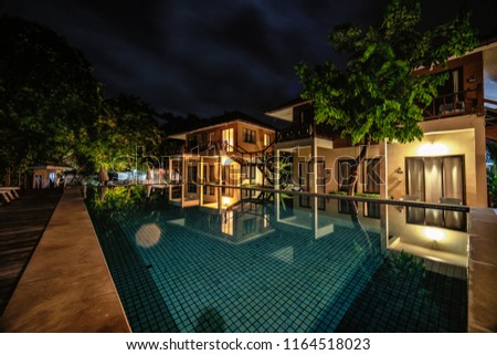 long exposure night shot image of poolside resort building with swimming pool and pool chairs along pool side at Samed Cabana Samed island Rayong Thailand