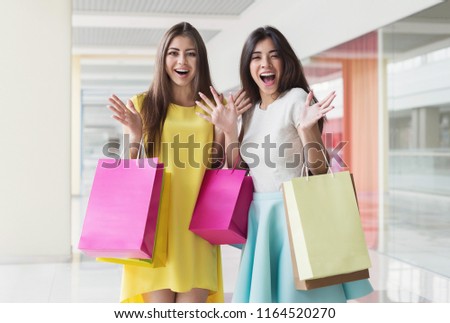 Surprised women with colourful bags in shopping center