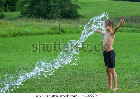 The boy with splash water in hot summer day outdoors