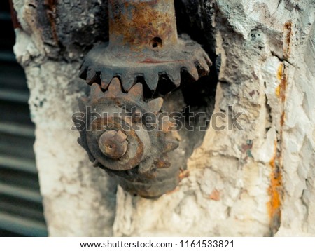 Rust steel engine gear meshing teeth city wall. Industrial iron stone background. Urban steel wheel. Work technology.
