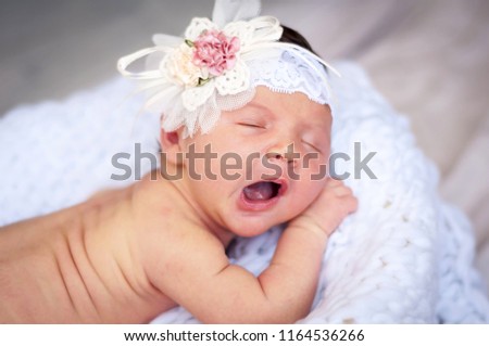 Cute tiny newborn Caucasian girl yawning closeup portrait. Kid bow elastic band on her head. A two week old infant baby girl stock image.