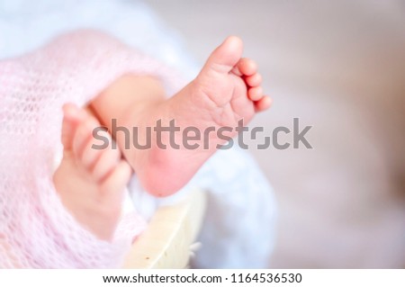 Tiny feet of a newborn baby girl wrapped up in a plaid slightly blurred image. One week old infant baby. Just born. First days of her life image.