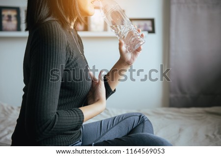 Asian woman having or symptomatic reflux acids,Gastroesophageal reflux disease,Drinking water Royalty-Free Stock Photo #1164569053