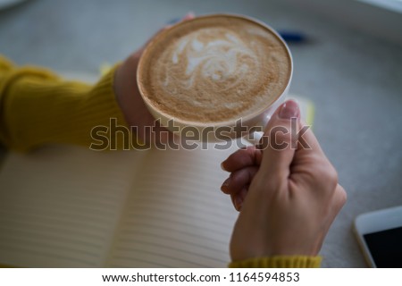 Female hands holding cup of coffee on table background. Coffee cup in coffee shop. Closeup image woman drinking hot coffee in cafe. Vintage style effect picture. Selective focus.