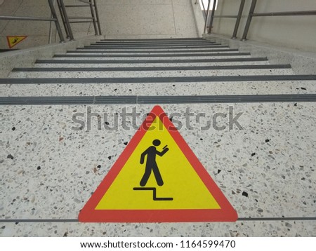 Warning icon floor leveling, mind your step. Walk down the stairs to be careful. Catch the railing at the stairs. Don't use smartphone temporary. Royalty-Free Stock Photo #1164599470