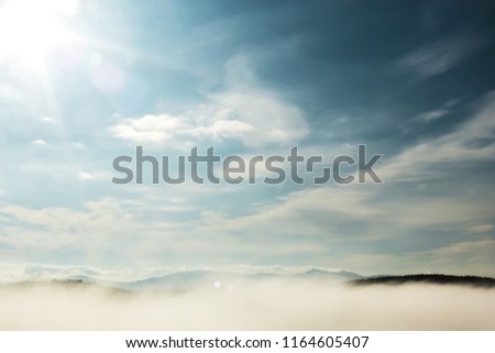 bright sun rays in blue morning sky with white clouds and fog