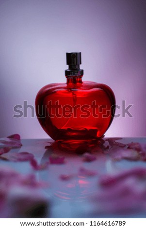 Perfume bottle with flower petals on gray background. Perfumery, cosmetics, fragrance collection