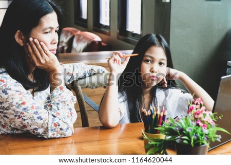 Mother and daughter sit and do their work irritably.