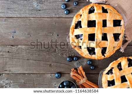 Rustic homemade blueberry pies with lattice pastry. Top view scene. Side border with copy space over a rustic wood background.
