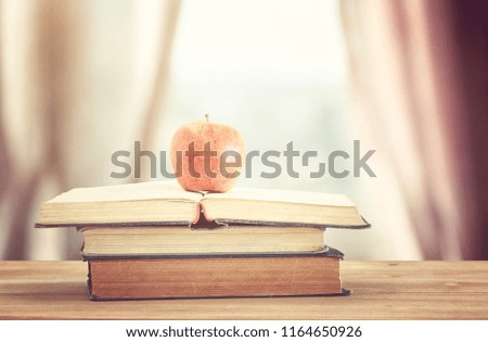 back to school concept. stack of books over wooden desk in front of day light window