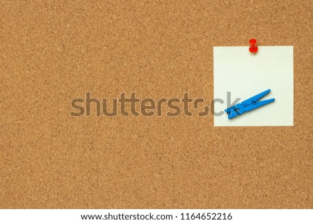 One colorful notes with red pushpins and clothespins isolated on a cork background