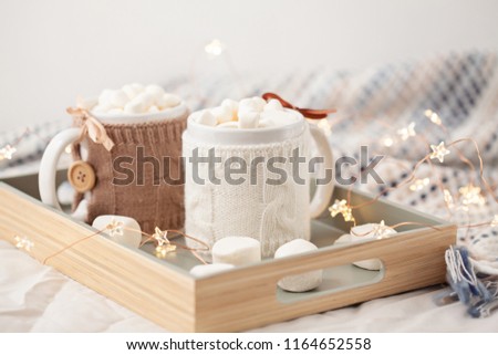Hot chocolate with marshmallows on soft plaid background with beautiful Christmas lights. Perfect winter time treat. 