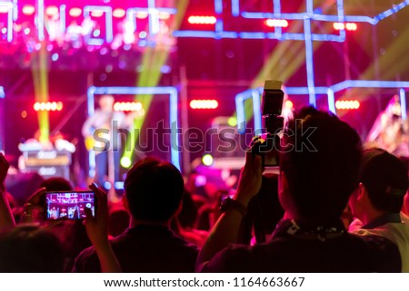 Crowd of hands up concert stage lights enjoying concert, and people fan audience silhouette raising hands in festival music rear view with spotlight glowing effect, blurred picture.