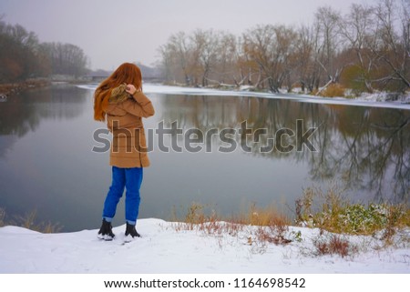 back, rear view of girl on  background of winter lake. moving Girl enjoying the view of the frozen lake or river.woman in warm clothes down jacket standing in the snow back. landscape with frozen lake