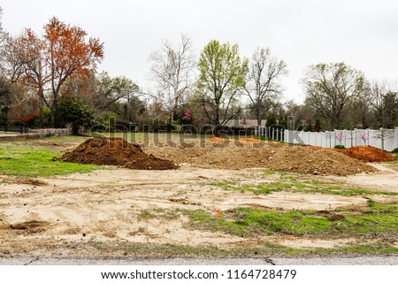 Piles of dirt hauled into vacant residential lot in early spring to prepared for construction Royalty-Free Stock Photo #1164728479