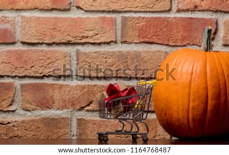 one orange pumpking and gift box in cart on brick wall background. Image with side cornet light