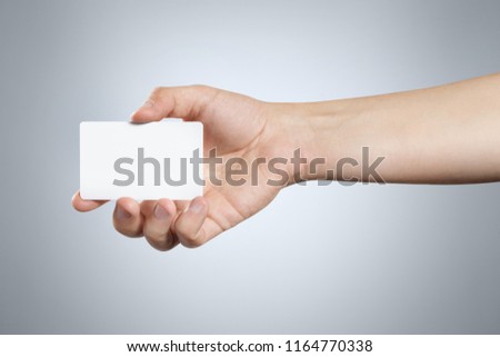 
Hand holding a blank card or a ticket/flyer, isolated on grey background