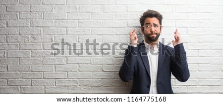Young friendly business man crossing his fingers, wishes to be lucky for future projects, excited but worried, nervous expression closing eyes Royalty-Free Stock Photo #1164775168