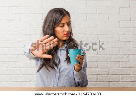 Young indian woman serious and determined, putting hand in front, stop gesture, deny concept