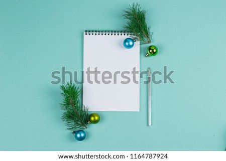 Christmas mock up blank greeting card. Fir tree branches and blue and green balls over green paper background. Flat lay. Top view. Copy space