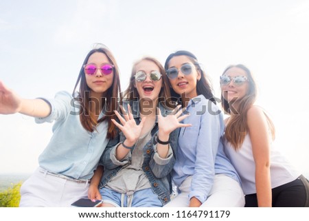 Best friends take selfies while walking in the Park. Four beautiful women wearing sunglasses are having a good day