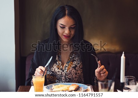 Amused girl trying to eat the food her boyfriend made for her in his first attempt of cooking.