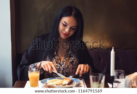 Lovely woman eating alone tasty food dressed in a elegant blouse at a well-known restaurant near her work place.