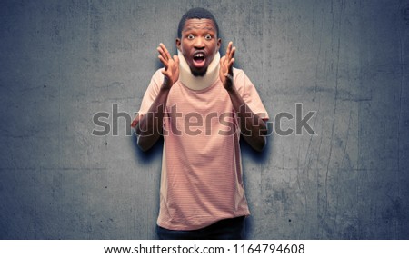 Injured african black man wearing neck brace stressful keeping hands on head, terrified in panic, shouting