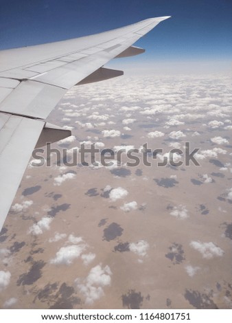Aerial shot of clouds over the sahara desert with plane wing