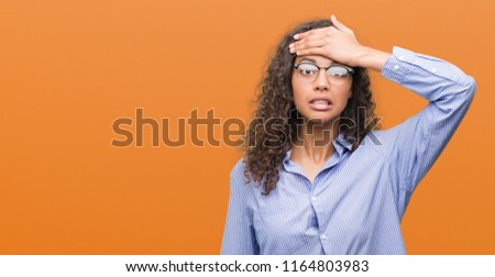 Beautiful young hispanic woman wearing glasses stressed with hand on head, shocked with shame and surprise face, angry and frustrated. Fear and upset for mistake. Royalty-Free Stock Photo #1164803983