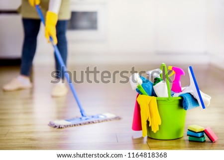 Bucket with cleaning items in modern kitchen with charwoman. Washing brush and spray set with copy space. Royalty-Free Stock Photo #1164818368