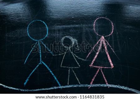 
child's family drawing on a chalkboard in school. crayons for drawing.