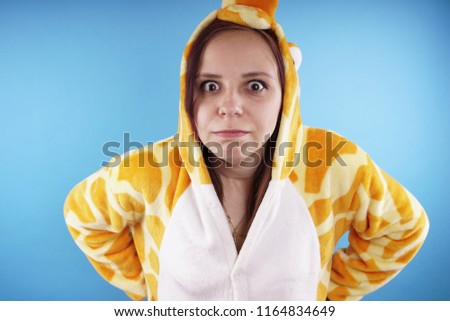 Girl in a bright children's pajamas in the form of a kangaroo. emotional portrait of a student. costume presentation of children's animator. Slippers in the form of cat's paws.            