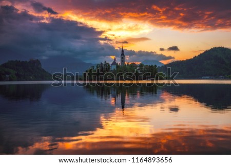 Dramatic sunrise on lake Bled, sunrise view on Bled lake, island, Pilgrimage Church of the Assumption of Maria and Castle with mountain range (Stol, Vrtaca, Begunjscica). Bled, Slovenia,