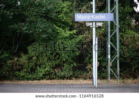 Two loudspeakers as well as the place sign of the platform Mainz Kastel on a metal mast.                             