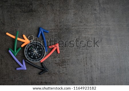 Uncertain path or multiple random life fortune and directions concept, compass at the center with magnet arrows pointing random multi directions on dark black chalkboard cement wall with copy space. Royalty-Free Stock Photo #1164923182