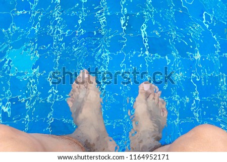 Man sitting and swinging his legs and feet in swimming pool for relaxation, sport and health
