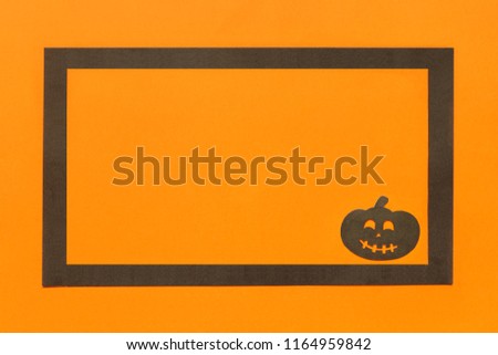 Halloween background. Black paper pumpkin in black frame on orange background Happy halloween concept, space for text. Top view. Mockup, Layout Flat lay