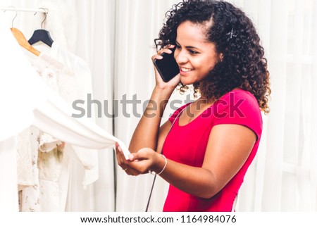 African american woman shopping and using smartphone choosing clothes in a store.fashion shopping concept