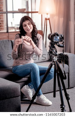 Sharing experience. Alert beautiful blogger holding a brush while making a new video for her blog